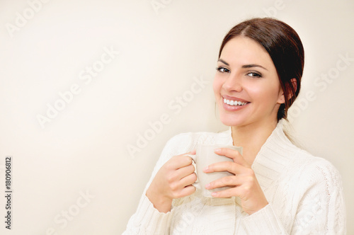 Young woman with long hair and brown eyes drinking coffee or tea from a cup