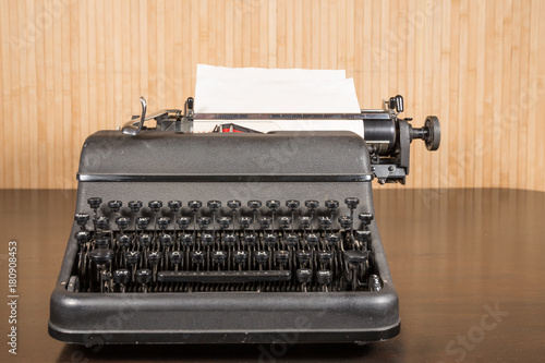 Old typewriter with blank paper on wooden table