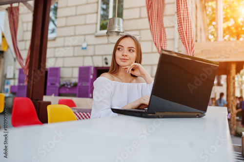 Portrait of a strong independent successful businesswoman wearing smart casual clothing and glasses working on a laptop in a cafe.