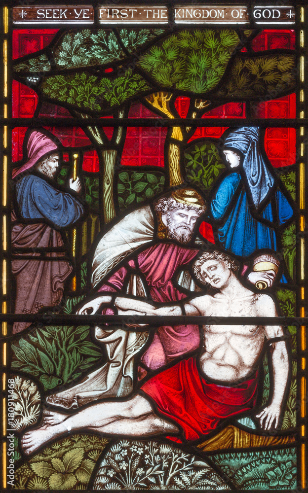 LONDON, GREAT BRITAIN - SEPTEMBER 19, 2017: The Parable of the Good Samaritan  on the stained glass in St Mary Abbot's church on Kensington High Street.