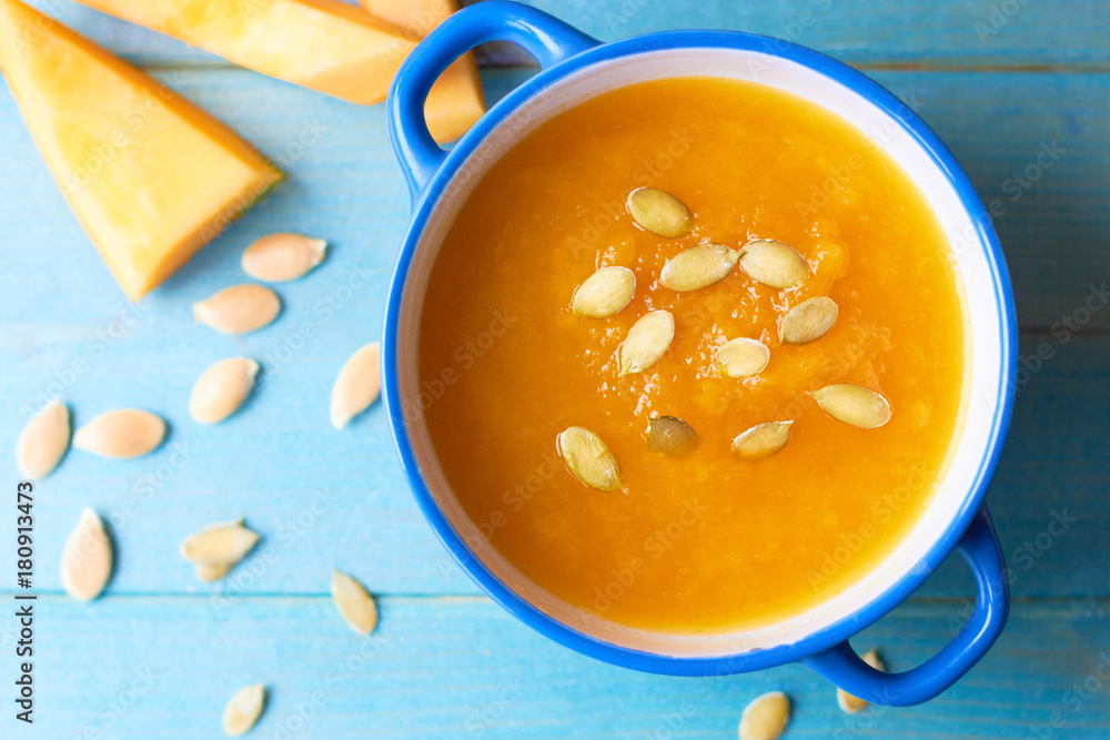 Appetizing pumpkin soup with seeds on a wooden background Appetizing pumpkin soup with seeds on a wooden background
