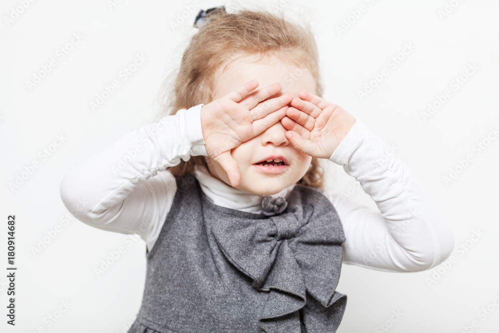 A little curly girl covered her eyes with her hands A little curly girl covered her eyes with her hands