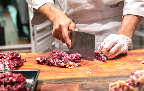 Chef cutting fresh raw meat on wooden board