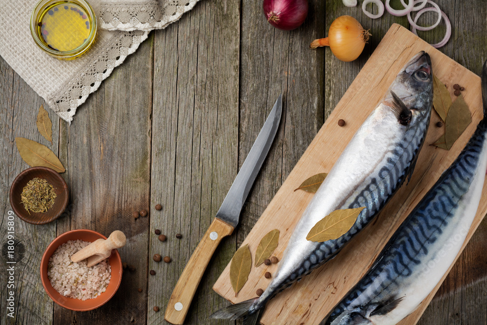 Raw mackerel fish with ingredients for cooking on a wooden old background. Selective focus. Rustic style. Top view. Raw mackerel fish with ingredients for cooking on a wooden old background. Selective focus. Rustic style. Top view.
