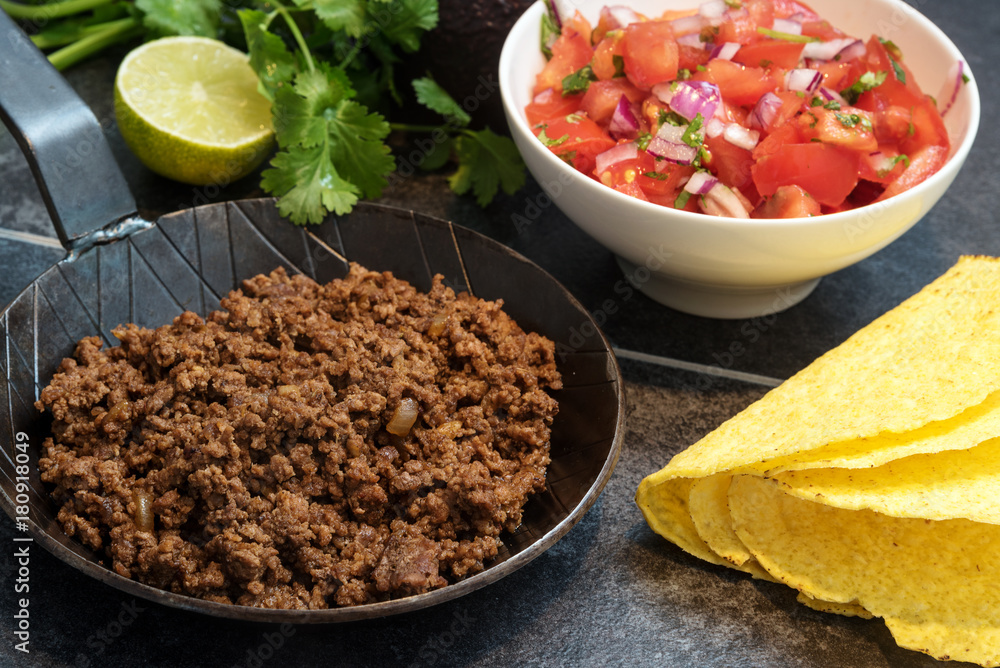 Fotografie fried ground beef in a pan, as a filling for taco shells with ingredients as tom