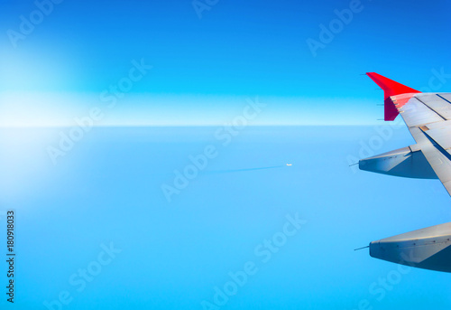 Aviation background with a blue sky and sea landscape. Wing of an airplane with place for your design or signature.