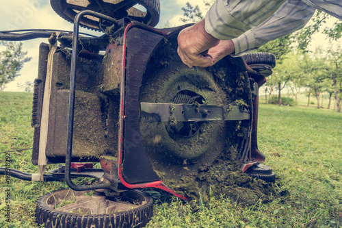 Man cleaning lawn mower blade.