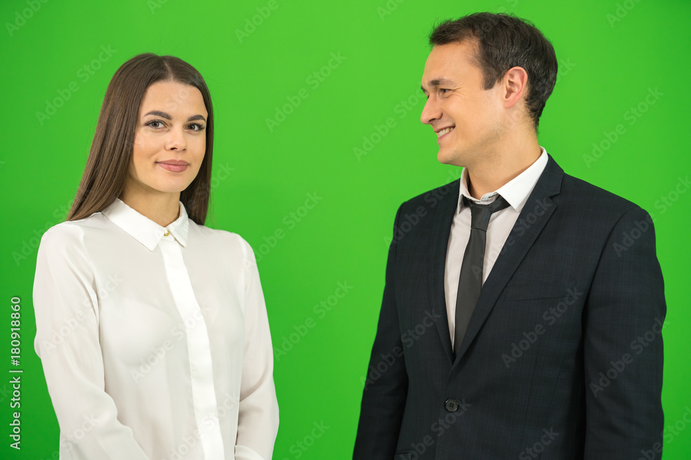 The happy businessman and businesswoman stand on the green background