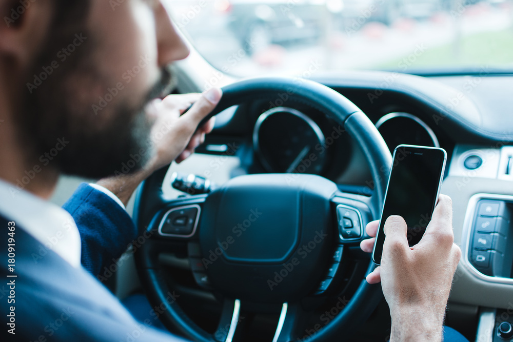 looking best way to get to office. Rear view of young businessman using his smart phone while sitting in car looking best way to get to office. Rear view of young businessman using his smart phone while sitting in car