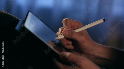 Closeup shot of designer's hand drawing a picture using tablet with stylus at home. Artist make work. Painter is sketching.