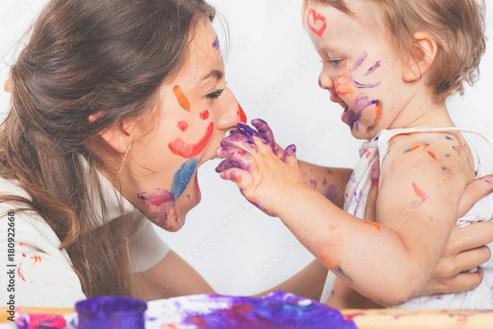 Obraz premium Happy mom and baby playing with painted face by paint
