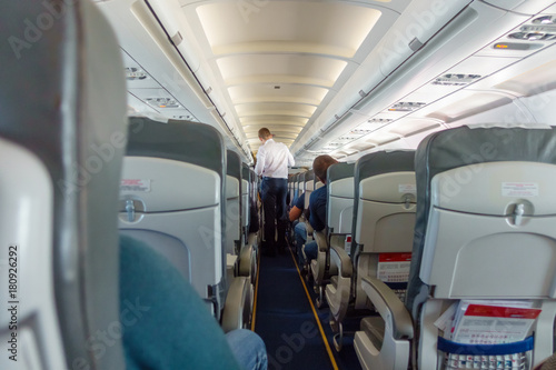 Steward offers food and drinks to economy class passengers on the plane