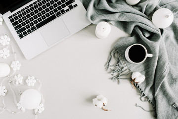 Home office workspace with laptop, plaid, candles, cotton balls and Christmas decorations. Flat lay, top view holiday composition.