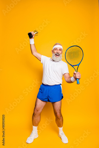 Wow! Competetive best cool healthy modern successful active grandpa with big tennis equipment and reward raised in hand up. Healthcare, weight loss, bodycare, motivation, pride, hobby © deagreez