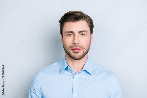close up portrait of successful brunet man looking at camera with kind and a little bit tricky glance while standing over grey background © deagreez