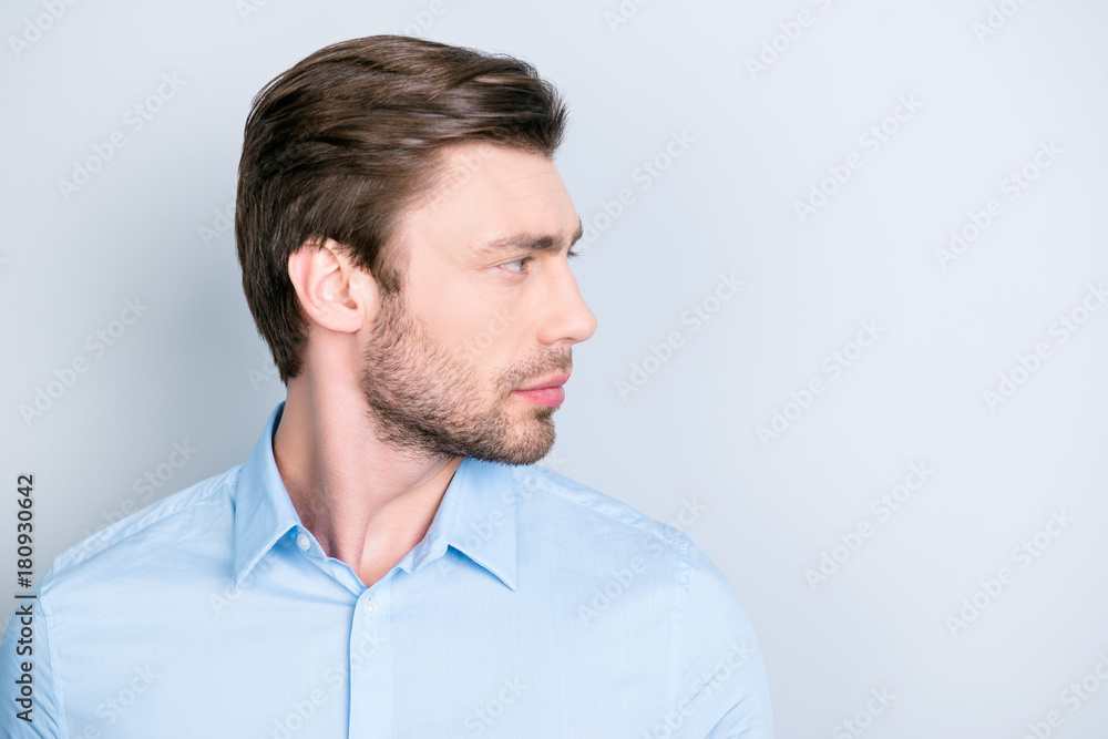 Isolated side view facial close up portrait of handsome confident serious man, looking to the side while standing on grey background Isolated side view facial close up portrait of handsome confident serious man, looking to the side while standing on grey background