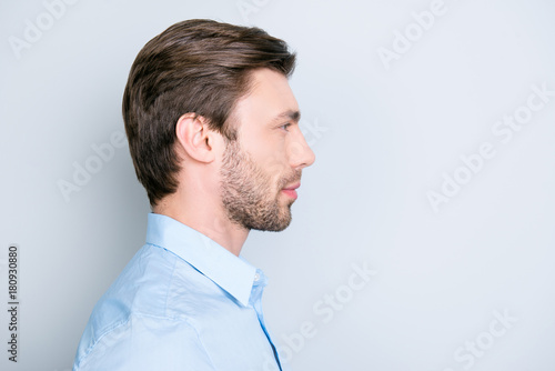 Close up side portrait of young bearded manager standing over grey background with copy space