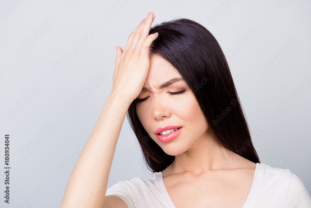 Close up portrait of confident entrepreneur having a headache, she has eyes closed and she is touching her forehead while standing over grey background. Stress and health care concept Close up portrait of confident entrepreneur having a headache, she has eyes closed and she is touching her forehead while standing over grey background. Stress and health care concept