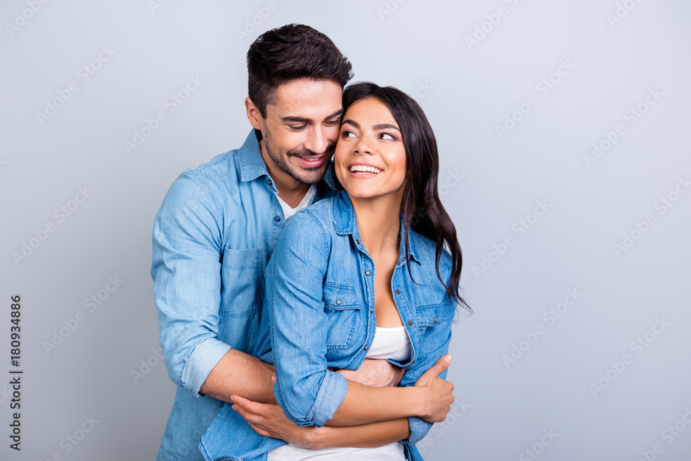 Concept of pregnancy and new parents. Happy excited husband is hugging his sweet wife and touching her tummy, isolated on grey background Concept of pregnancy and new parents. Happy excited husband is hugging his sweet wife and touching her tummy, isolated on grey background