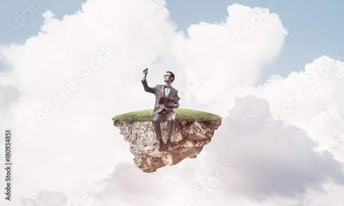 Young businessman or student floating in sky and studying the sc