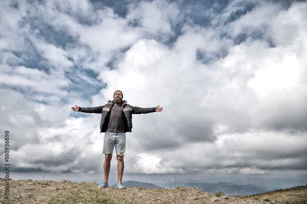 Hipster with serious face and raised hands at mountains. Hipster with serious face and raised hands at mountains.