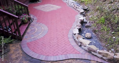 Aerial camera showing the full finished brick paver project with meandering edges, rock wall and custom two tone emblem. photo