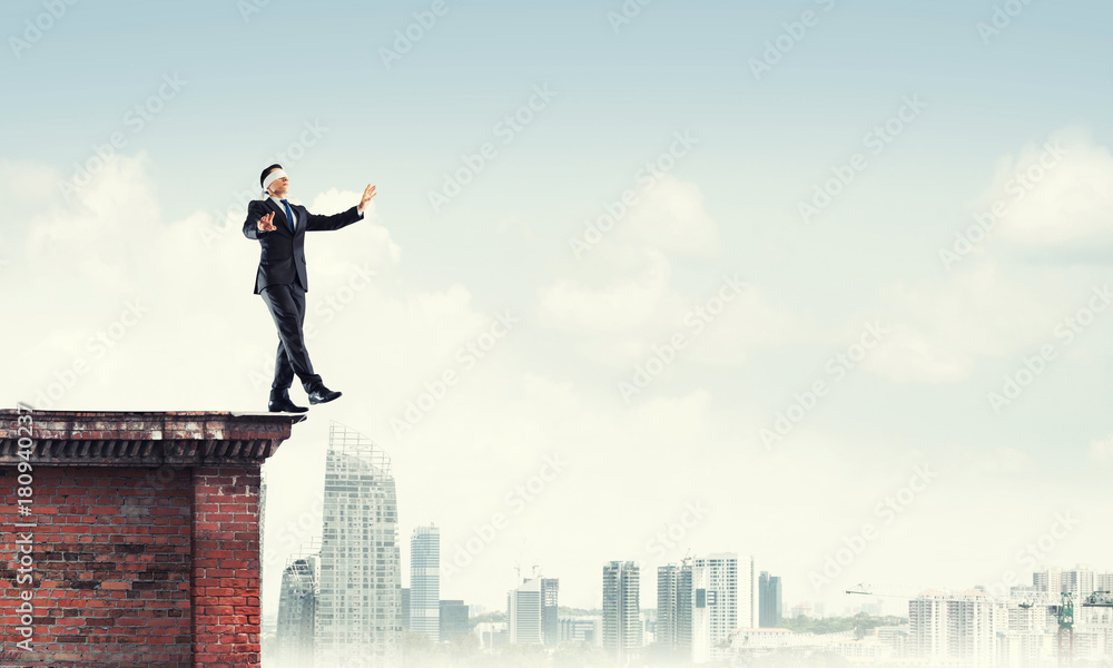 Danger and risk concept with businessman making step from edge Danger and risk concept with businessman making step from edge