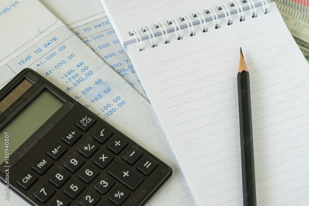 Financial salary man concept as pencil on white notebook with carbon salary slips and black calculator Financial salary man concept as pencil on white notebook with carbon salary slips and black calculator