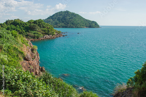 Beautiful seascape view of green hill, rock and long shore with blue sea in the background.