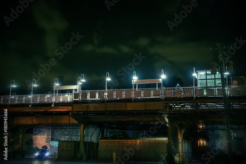 Dark urban Chicago city scene at night with an elevated train platform  person  car and alley.