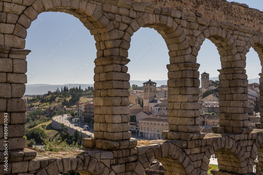 view of the village through the ancient roman aqueduct bridge in Segovia Spain.