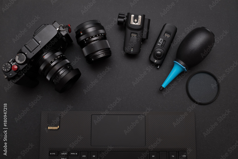 top view of photographer work space with mirrorless camera system, Dust blower, Lens filter, Wireless flash trigger, and SD card on laptop top view of photographer work space with mirrorless camera system, Dust blower, Lens filter, Wireless flash trigger, and SD card on laptop