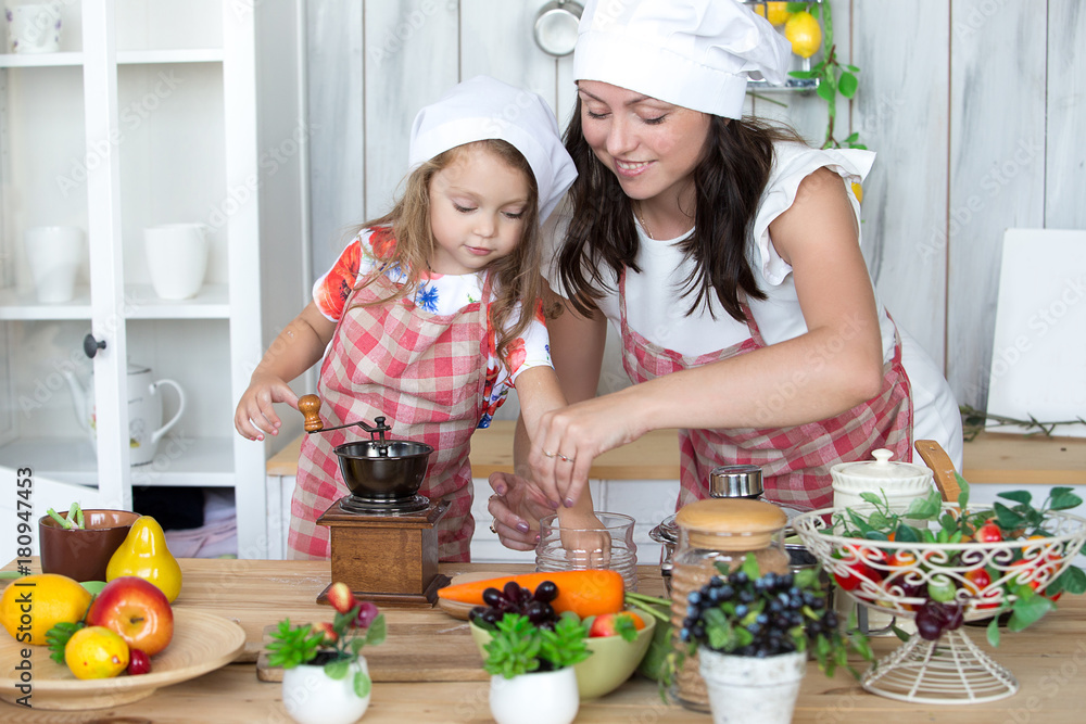 Mother and daughter cook dinner together in the kitchen. Portrait, childhood, family values. Mother and daughter cook dinner together in the kitchen. Portrait, childhood, family values.