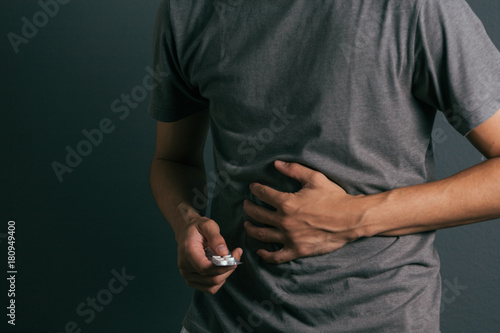 Young man with pack of pills feels stomach ache