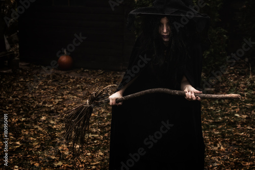 Konstfotografi Wicked looking witch holding a broom in a rural autumn scene.