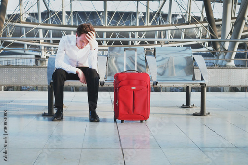 flight delay or problem in the airport, tired desperate passenger waiting in the terminal with suitcase