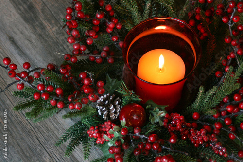 Festive Holiday Christmas Candle with Pine Tree Branches and Berries Over Rustic Wood Background photo