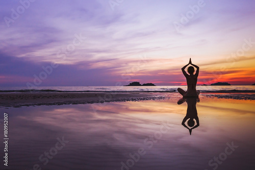 Fototapeta mindful meditation background, silhouette of woman doing yoga on the beach at su