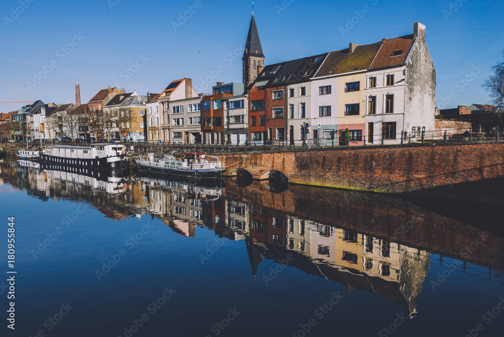 December, 27th, 2016 - Ghent, East Flanders, Belgium. Portus Ganda marina with colorful belgian houses, private boats and barges in docks reflected on the water of canal in flemish city Gent.