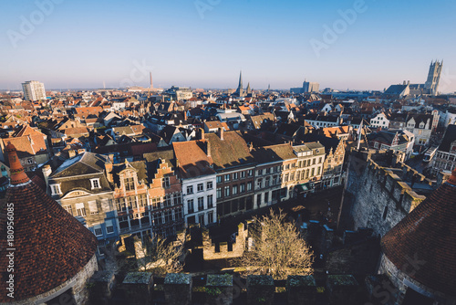 Ghent, Flanders, Belgium - December 30th, 2016. Gent Old town panoramic view from above Gravensteen castle. Ghent skyline with merchant houses roofs, St. Bavo and St.Jacob's cathedrals by golden hour.