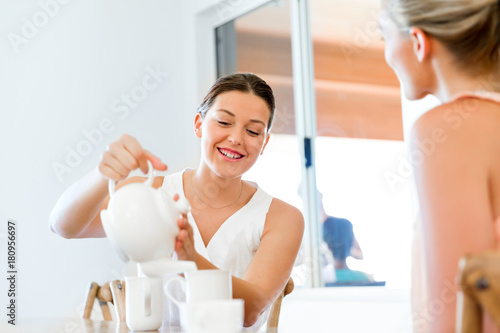 Young woman with her friend having tea at home