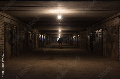 Man in the long hallway with metal gates