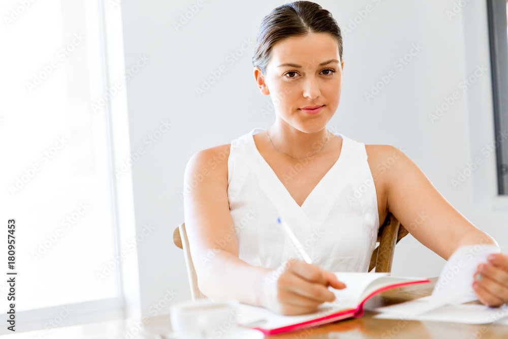 Young woman writing in an agenda at home or office Young woman writing in an agenda at home or office