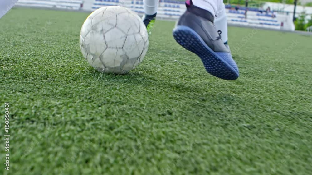 Tracking of legs of unrecognizable boy dribbling soccer ball passed his