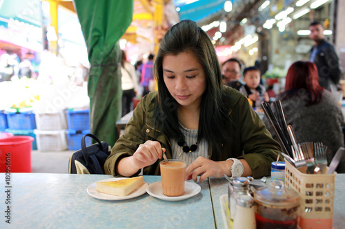 Photography girl have breakfast in the cafe in chinese asian wet market