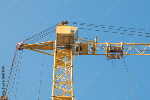 Construction tower crane against the background of the blue sky skyline close photo