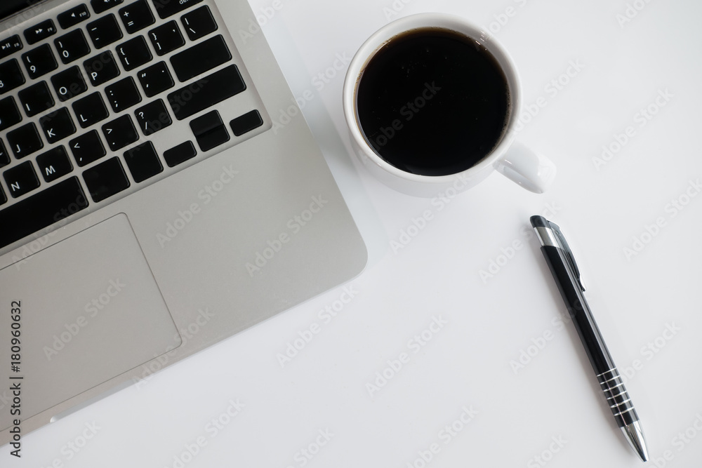 White office desk table with blank notebook, laptop computer, cup of coffee and supplies. Top view, flat lay. White office desk table with blank notebook, laptop computer, cup of coffee and supplies. Top view, flat lay.