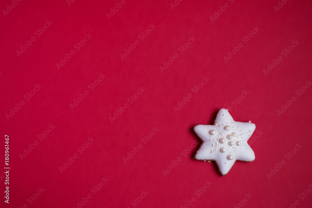 Gingerbread star with white icing and sprinkles on red background Gingerbread star with white icing and sprinkles on red background