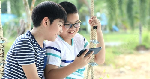 Happy asian chikd hand holding mobile phone on swing chair with smile face. photo