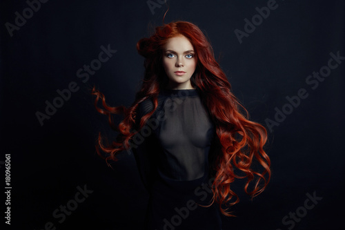 Murais de parede Portrait of redhead sexy woman with long hair on black background